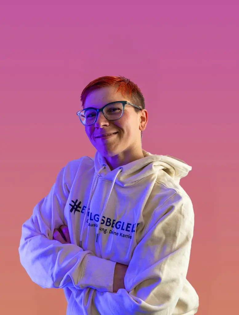 Theresa, Automotive Karrierebotschafterin, lächelt mit Brille und Hoodie.